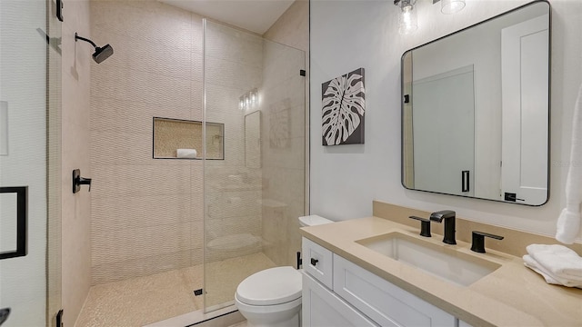 bathroom with vanity, toilet, and a shower with door