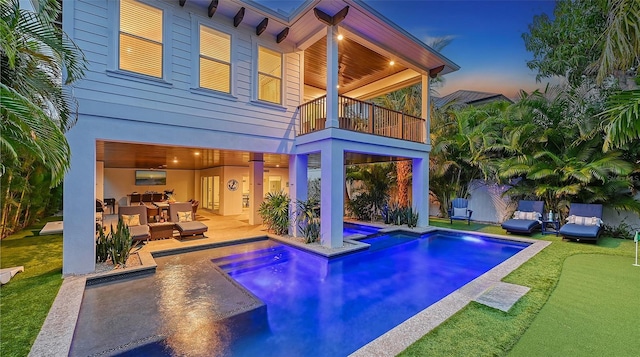 pool at dusk with a jacuzzi and a patio