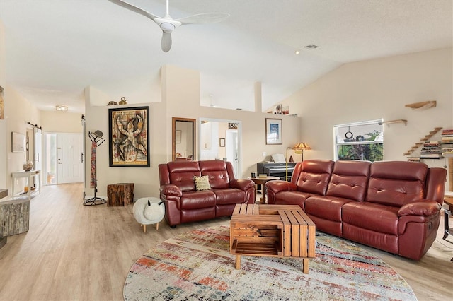 living room featuring visible vents, stairway, light wood-style floors, a ceiling fan, and high vaulted ceiling