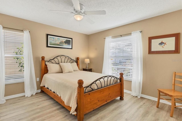 bedroom with a textured ceiling, light wood finished floors, a ceiling fan, and baseboards