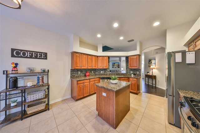 kitchen featuring backsplash, appliances with stainless steel finishes, a center island, and dark stone counters