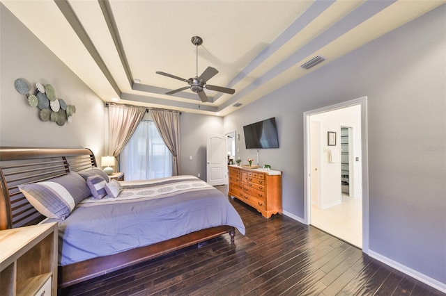 bedroom with ceiling fan, dark hardwood / wood-style flooring, and a tray ceiling