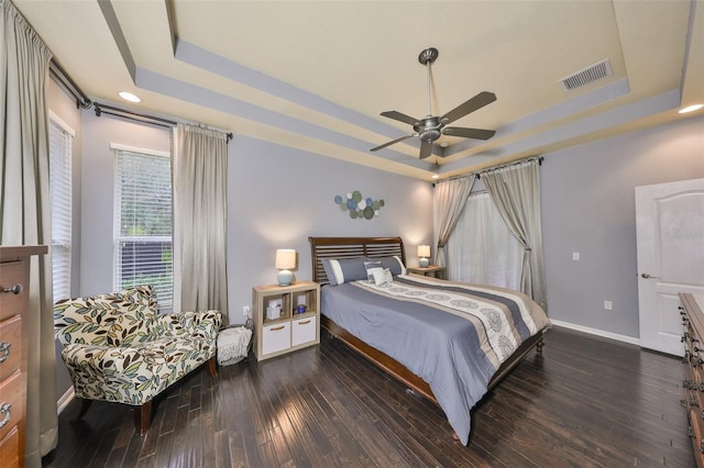 bedroom with ceiling fan, dark hardwood / wood-style floors, and a raised ceiling