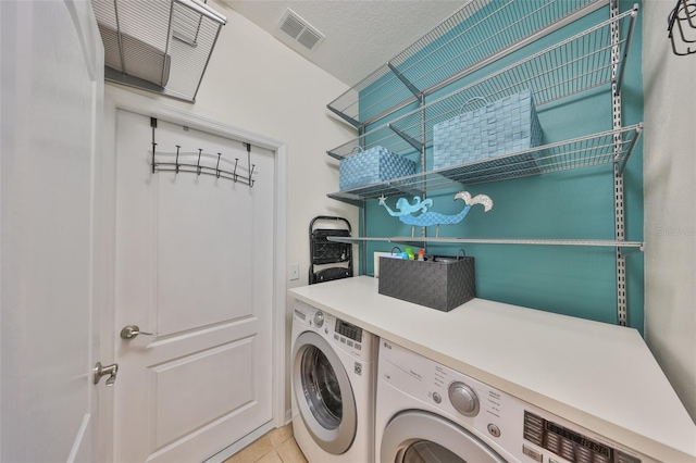 washroom with washer and dryer, a textured ceiling, and light tile patterned flooring