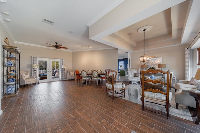 living room with dark hardwood / wood-style floors, ceiling fan with notable chandelier, ornamental molding, a tray ceiling, and french doors