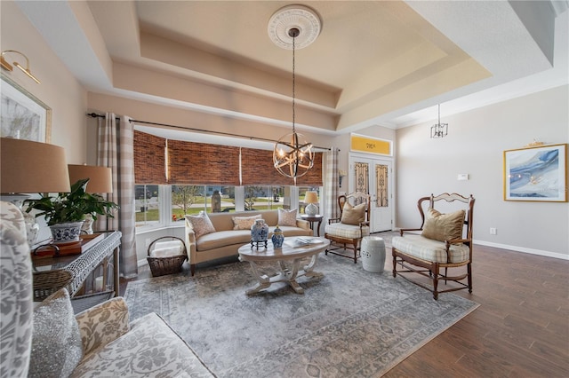 living room featuring a chandelier, a tray ceiling, and dark hardwood / wood-style flooring