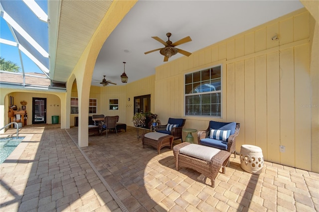 view of patio with ceiling fan, outdoor lounge area, and glass enclosure