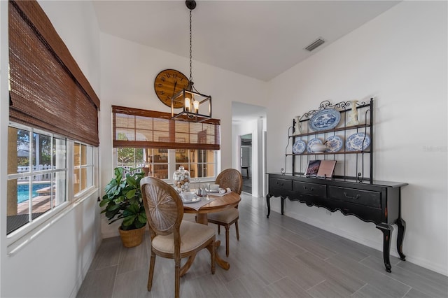 dining space with an inviting chandelier, a towering ceiling, and wood-type flooring