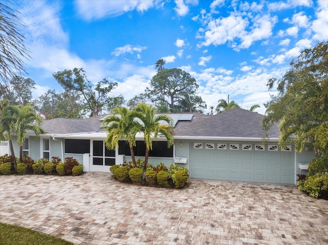 ranch-style home with a garage and solar panels