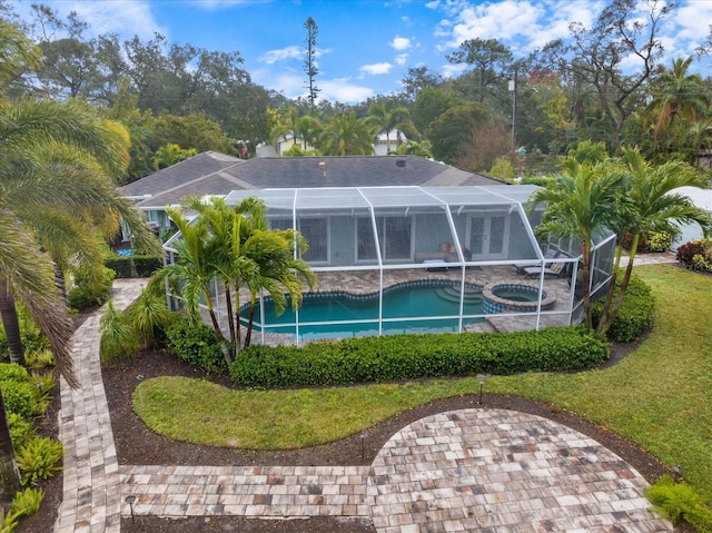 back of property featuring a yard, a lanai, and a pool with hot tub