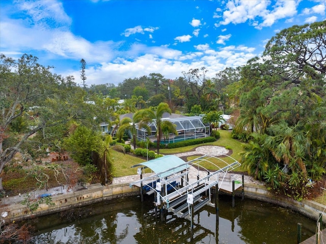 view of dock with a water view, glass enclosure, and a lawn