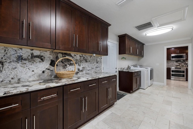 kitchen with washer and clothes dryer, stainless steel appliances, light stone counters, dark brown cabinetry, and ornamental molding