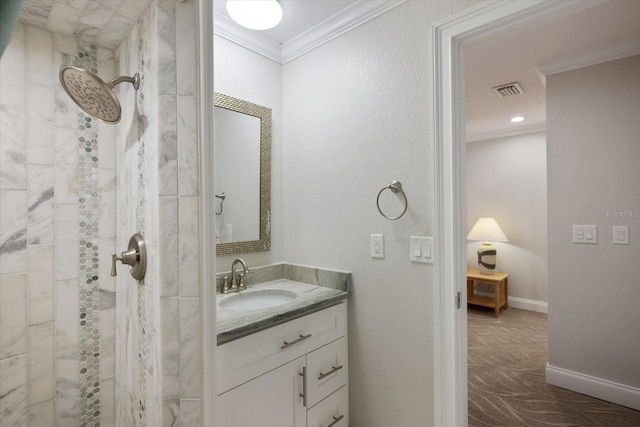 bathroom with ornamental molding, a tile shower, and vanity