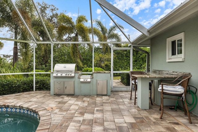 view of patio / terrace with exterior kitchen, a lanai, area for grilling, and an outdoor bar