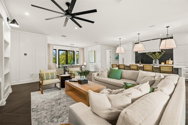 living room featuring dark parquet flooring and ceiling fan