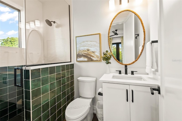 bathroom featuring vanity, a wealth of natural light, toilet, and a tile shower