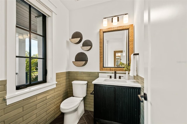 bathroom featuring vanity, tile patterned floors, tile walls, and toilet