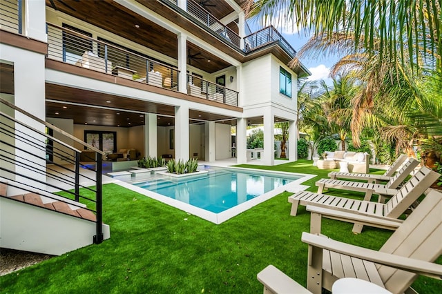 rear view of property featuring ceiling fan, a patio area, a balcony, and a lawn