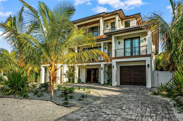 view of front of property featuring a garage, french doors, and a balcony