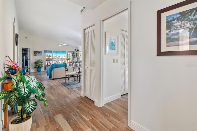 hall with vaulted ceiling and hardwood / wood-style floors