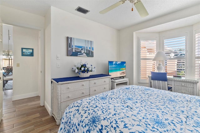 bedroom with hardwood / wood-style flooring, ceiling fan, and a textured ceiling