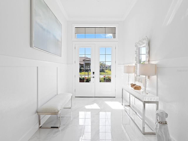 doorway to outside with marble finish floor, a decorative wall, crown molding, and wainscoting