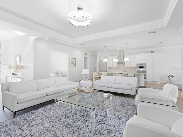 living room featuring a raised ceiling, ornamental molding, and hardwood / wood-style flooring