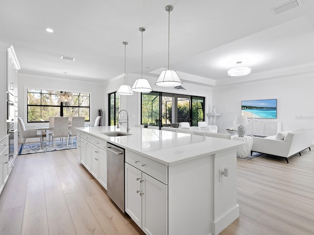 kitchen with hanging light fixtures, an island with sink, and white cabinets