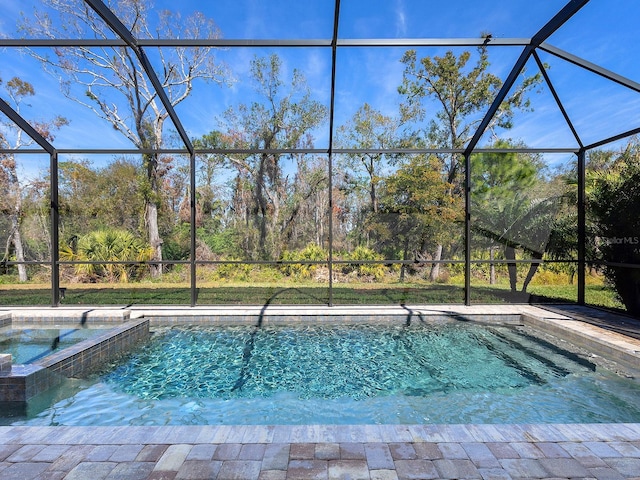 view of pool with a pool with connected hot tub, glass enclosure, and a patio