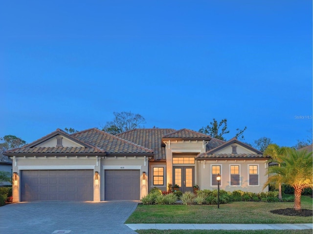 view of front of house with a garage, driveway, french doors, a tiled roof, and a front yard