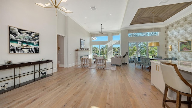 living room featuring crown molding, a towering ceiling, and light hardwood / wood-style flooring