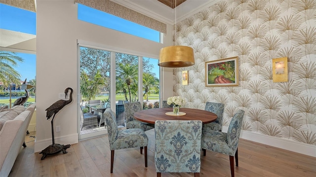 dining area featuring hardwood / wood-style flooring, ornamental molding, and a high ceiling