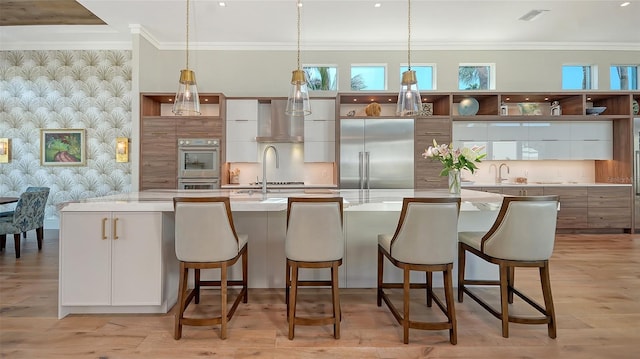 kitchen featuring appliances with stainless steel finishes, white cabinets, ornamental molding, light stone countertops, and a spacious island