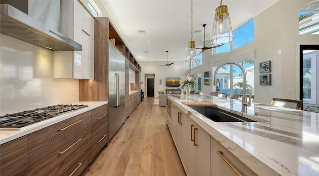 kitchen with white cabinetry, light stone countertops, stainless steel appliances, and wall chimney exhaust hood