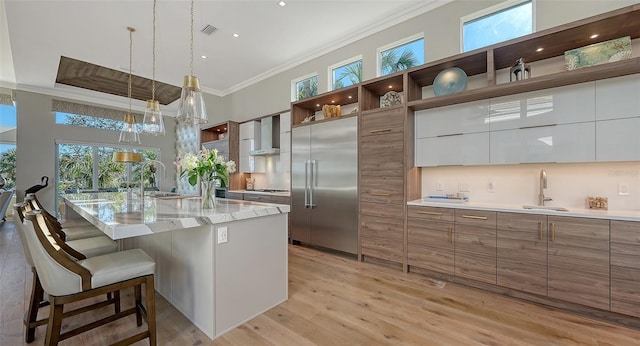 kitchen with a breakfast bar area, white cabinetry, crown molding, a center island with sink, and stainless steel appliances