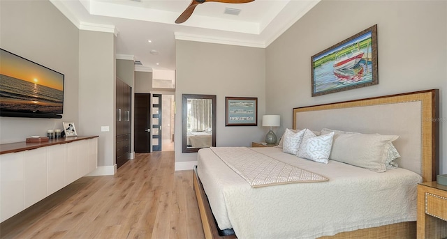 bedroom featuring a raised ceiling, ornamental molding, ceiling fan, and light hardwood / wood-style flooring