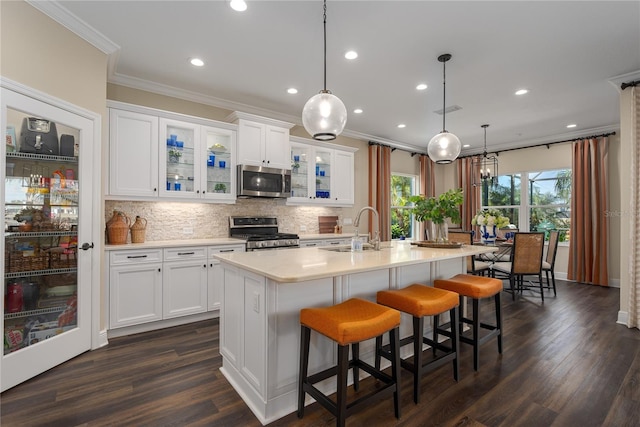 kitchen featuring white cabinetry, sink, stainless steel appliances, and a center island with sink