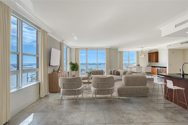 tiled living room with sink, a wall of windows, and ornamental molding