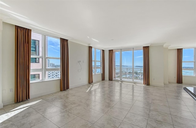 tiled spare room with a water view, a wall of windows, and ornamental molding