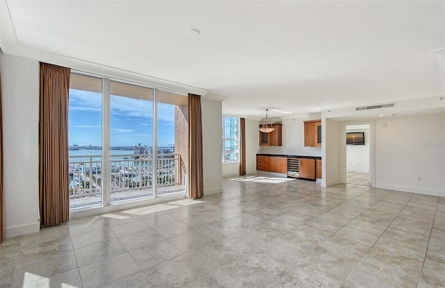 unfurnished living room featuring a water view, ornamental molding, and expansive windows