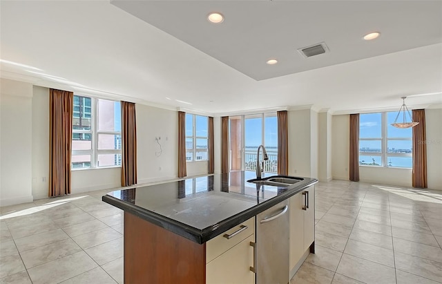 kitchen featuring sink, a water view, a center island with sink, stainless steel dishwasher, and white cabinets