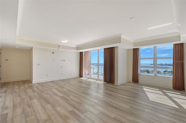 empty room featuring ornamental molding, a water view, and light wood-type flooring