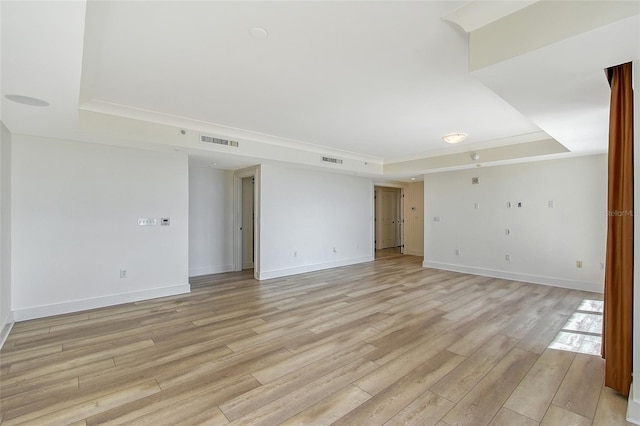 unfurnished room with a tray ceiling and light hardwood / wood-style flooring