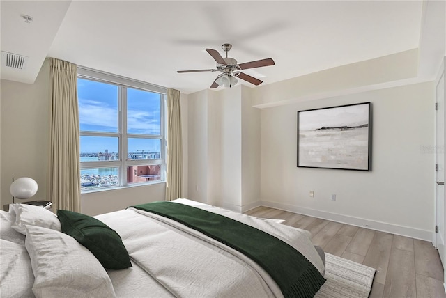 bedroom with ceiling fan, a water view, and light wood-type flooring