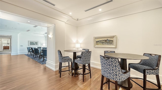 dining space with crown molding and wood-type flooring