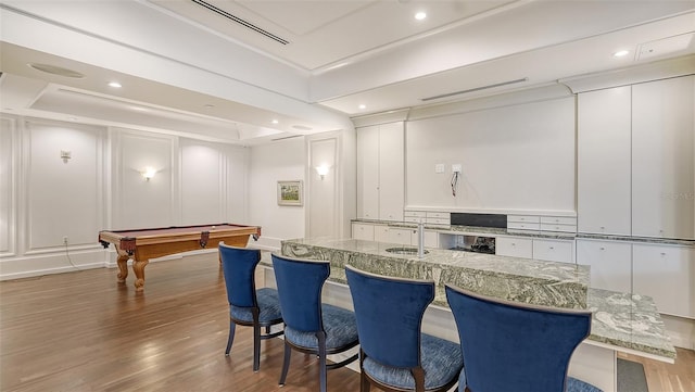 kitchen featuring hardwood / wood-style floors, billiards, sink, white cabinets, and light stone counters