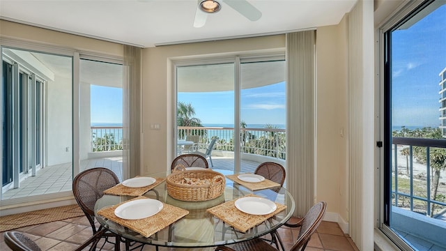 sunroom with ceiling fan and a water view