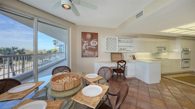 dining space with ceiling fan and tile patterned flooring