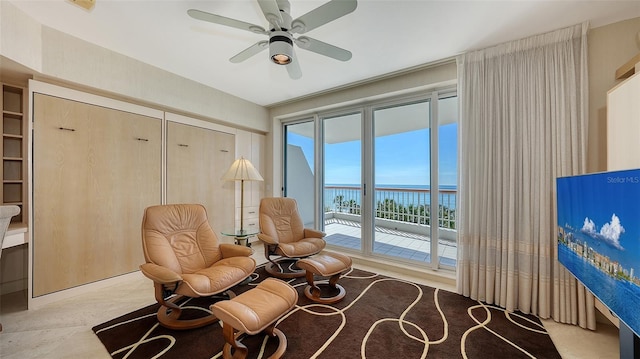 living area featuring ceiling fan and a water view