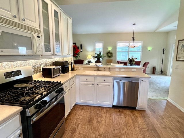 kitchen featuring white cabinetry, appliances with stainless steel finishes, decorative light fixtures, and kitchen peninsula